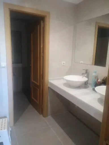 Cuarto de baño moderno con dos lavabos reformado por Obras Solum