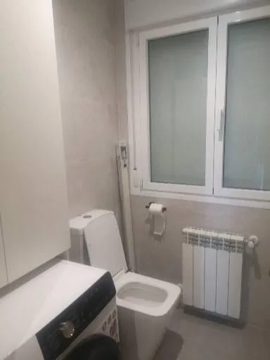 Baño minimalista con inodoro suspendido y radiador
